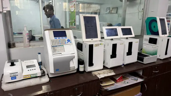A run of laboratory analysers along the pathology bench, each with its own screen and sample port.