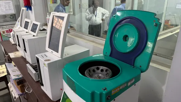 A laboratory centrifuge standing open with its rotor visible, alongside the analyser bench.