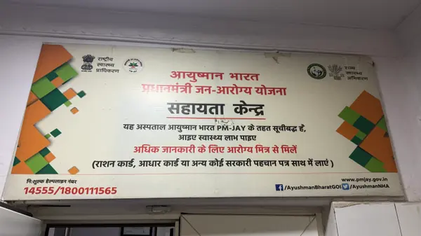 The Ayushman Bharat PM-JAY help desk board, giving the scheme helpline numbers and the documents to bring.