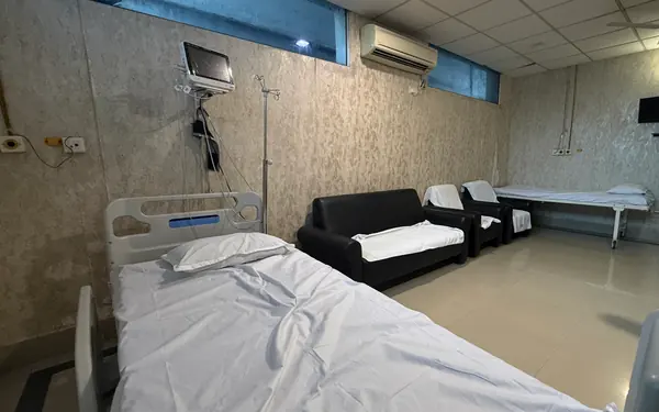 A private room with a bed, a monitor on the wall, an attendant sofa and an air conditioner.