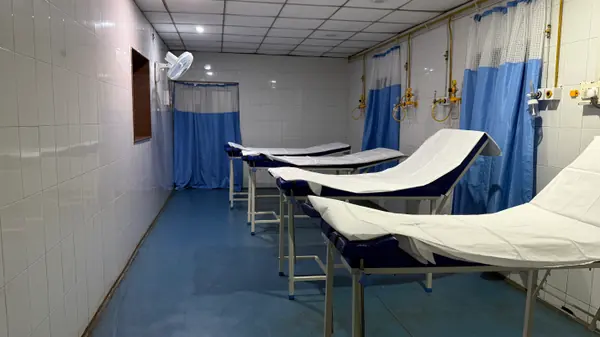 A recovery room with four examination couches made up, each with an oxygen point on the wall behind it.