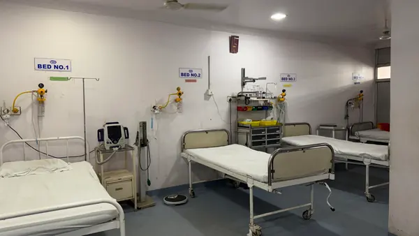 A ward with four numbered beds made up, each with an oxygen point and a monitor within reach.